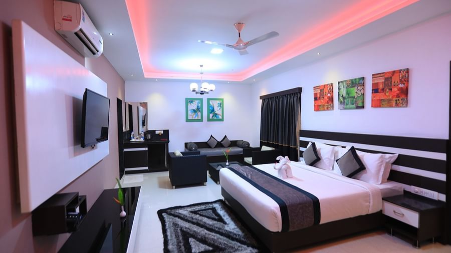 Image of a room with a bed, a television, and a seating area at Parampara Resort & Spa, Kushalnagar.